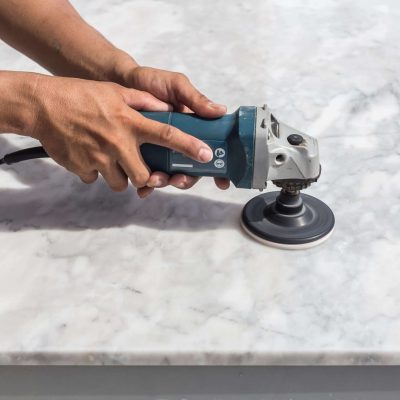 Man polishing marble stone table by small angle grinder